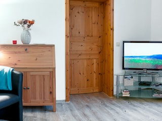 Wohnzimmer mit TV und Tür zum Schlafzimmer