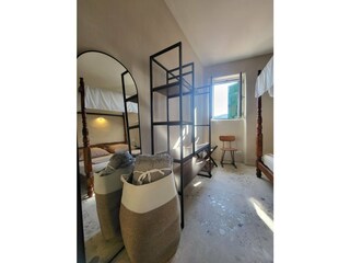 Schlafzimmer mit Himmelbett und offenem Kleiderschrank