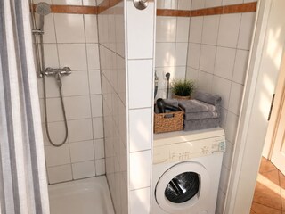 Dusche und Waschmaschine im Badezimmer.