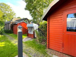 Blick auf das Saunahaus, Strandkorb und Gartenhaus.