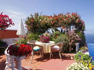 Terrasse am Pool mit Tisch und Korbstühlen