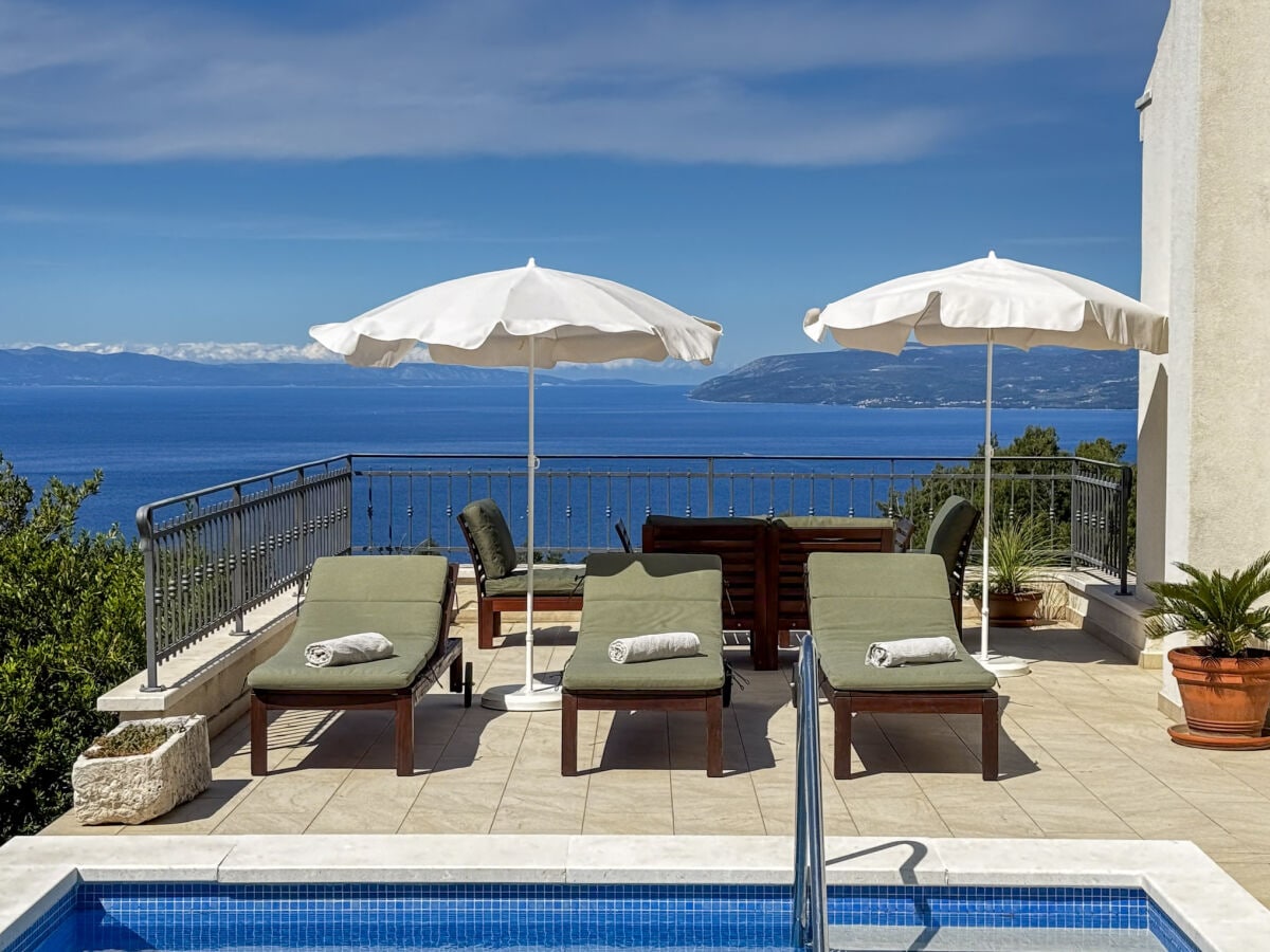 Terrasse am Pool mit Sonnenliegen und Meerblick