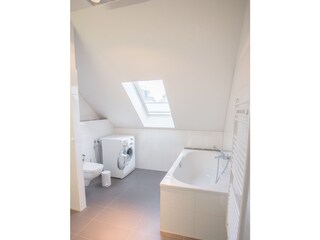 Großes Badezimmer mit Wanne und Waschmaschine
