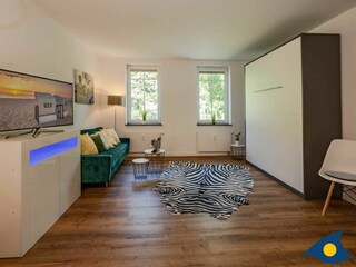 Wohnbereich mit Couch und Bett mit Schlaffunktion