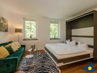 Wohnbereich mit Couch und Bett mit Schlaffunktion