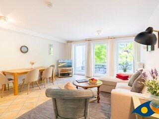 Wohnzimmer mit Schlafcouch und Zugang zum Balkon