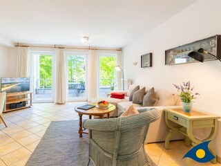 Wohnzimmer mit Schlafcouch und Zugang zum Balkon
