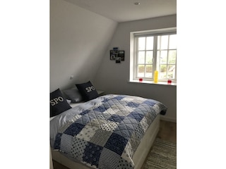 Schlafzimmer mit Doppelbett und TV