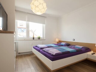 Das lichtdurchflutete Schlafzimmer mit großem Doppelbett